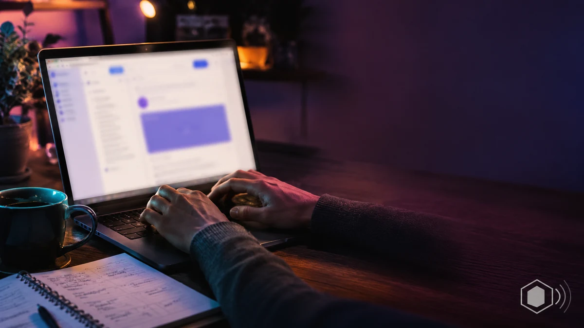 Hands typing an email newsletter on a laptop in a home office at night