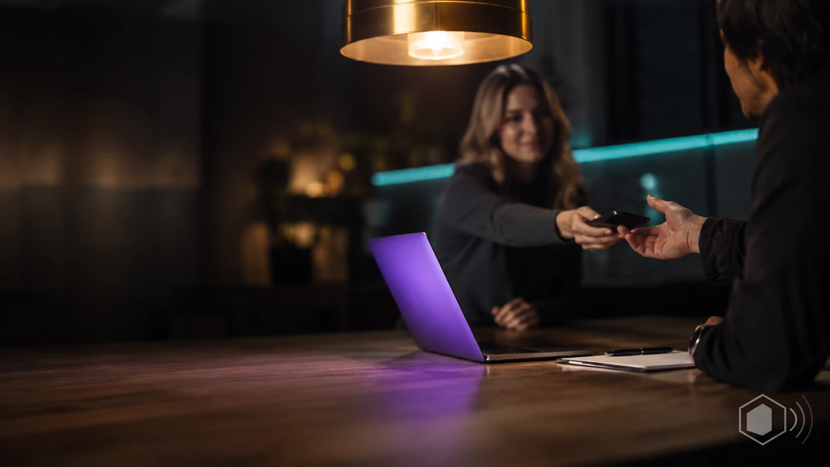 Business owner handing her phone to a marketing professional across a table